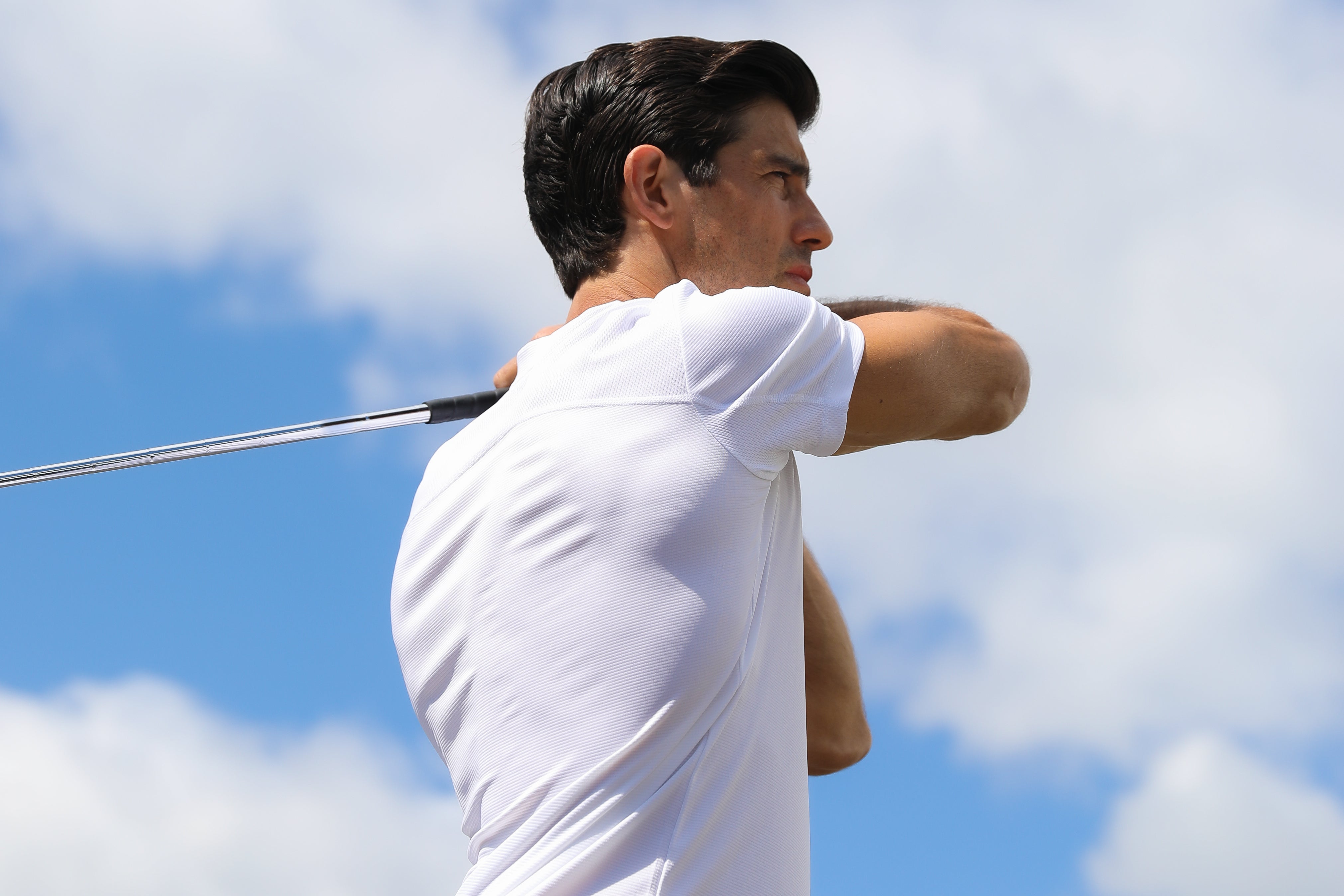 Man in Truwear white short-sleeved golf shirt in the middle of a golf swing