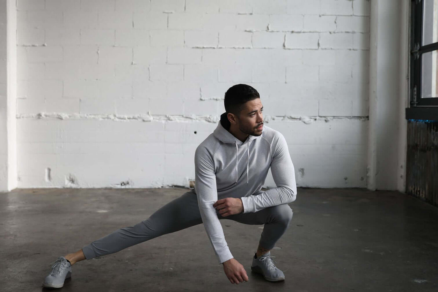 Man stretching in Truwear gray hoodie, jogging pants, and shoes